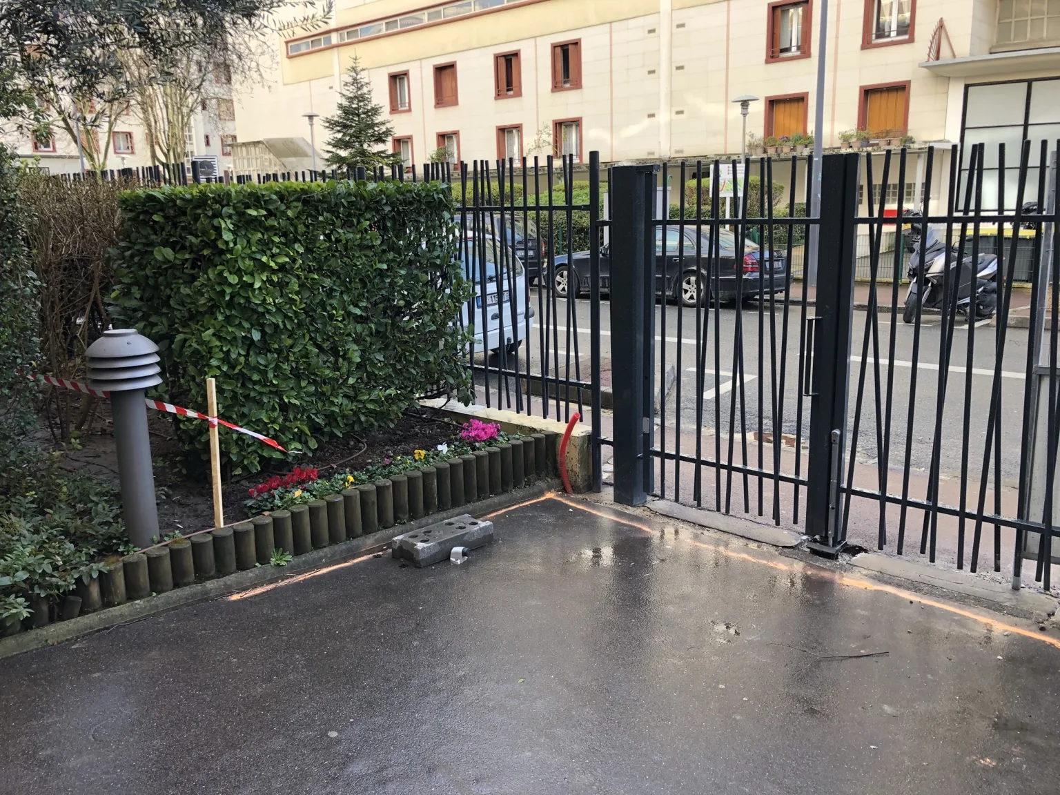 Portillon noir intégré à une clôture dans un cadre végétalisé